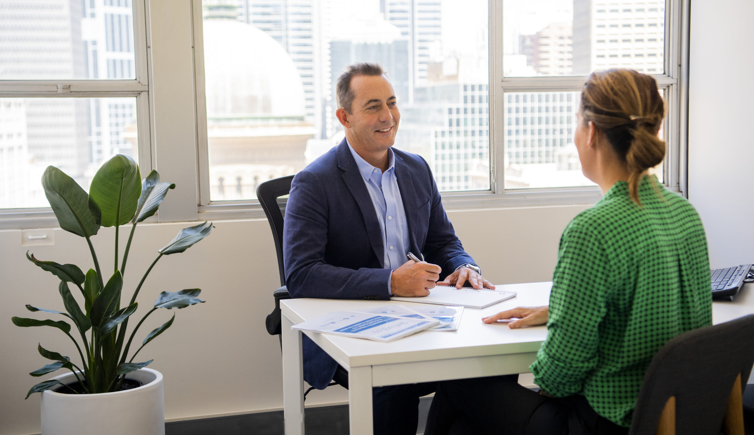 A man and woman talking at a desk in an office.