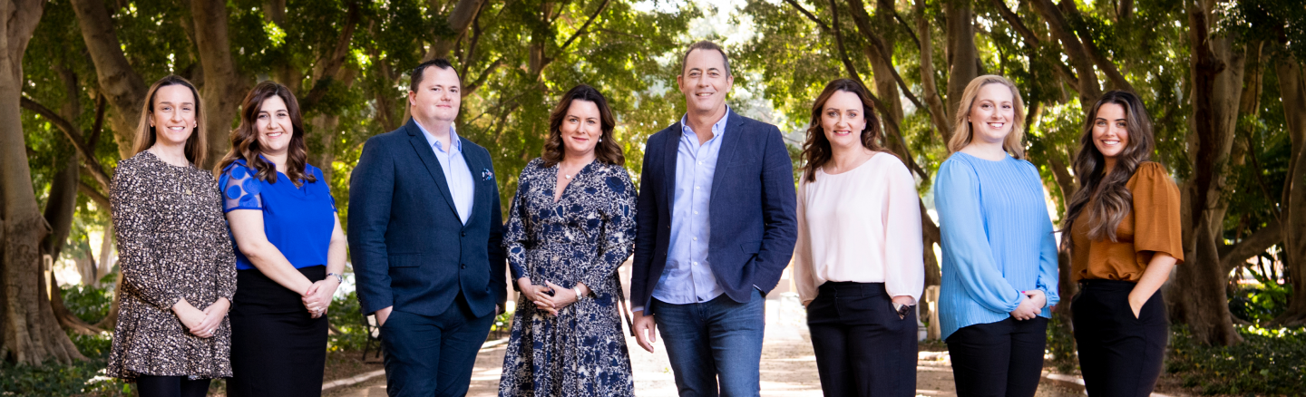 A group of people standing in front of trees.